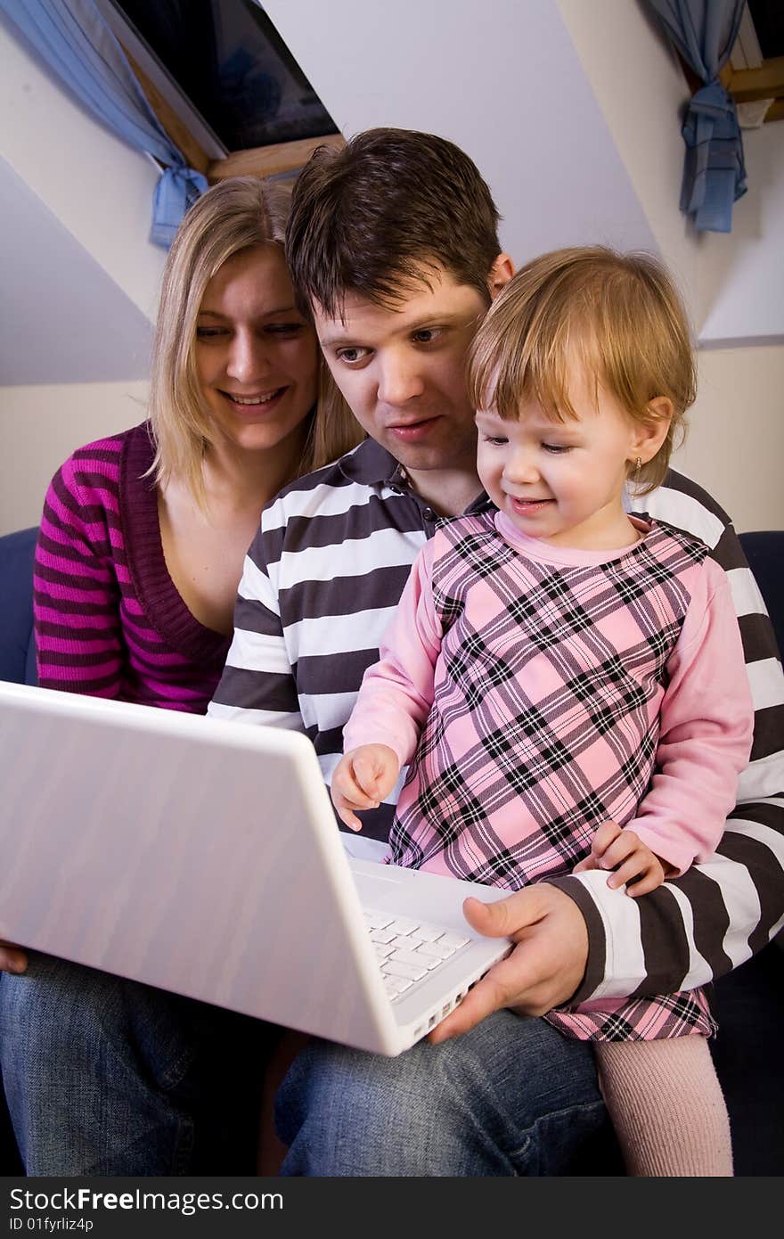 Little girl with parents play with a laptop