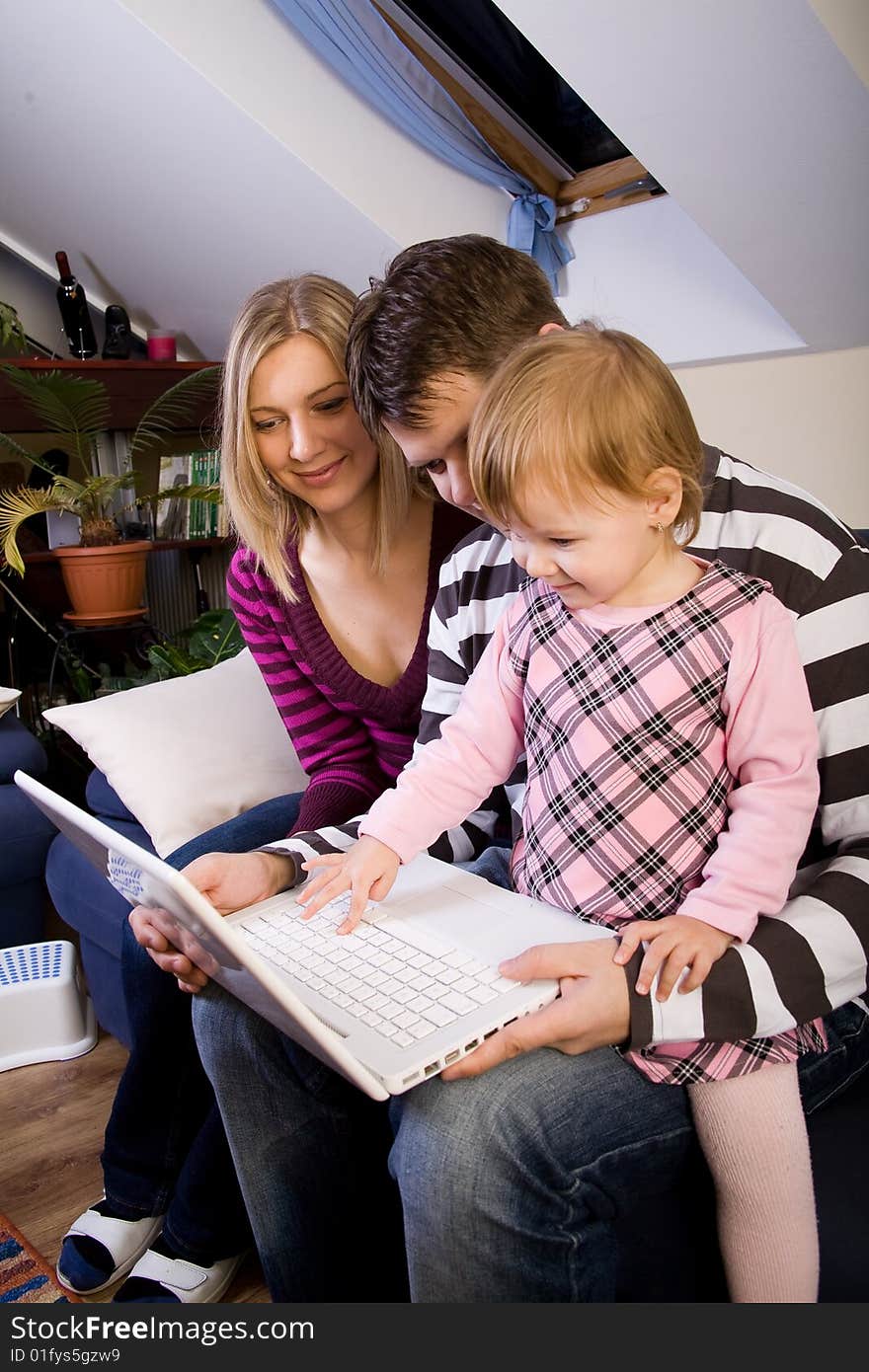 Little girl with parents play with a laptop