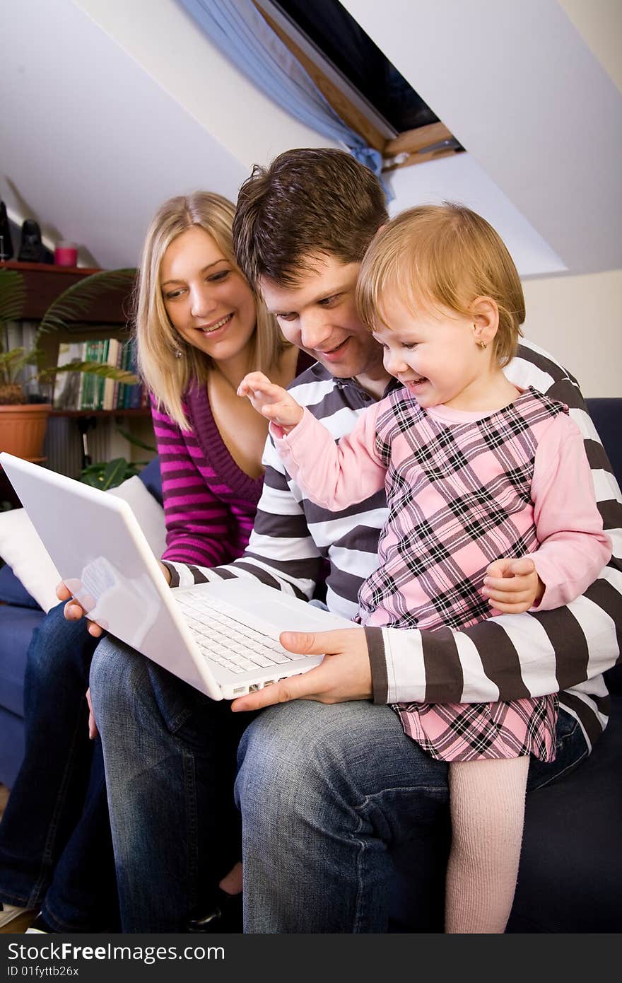 Little girl with parents play wit a white laptop compute. Little girl with parents play wit a white laptop compute