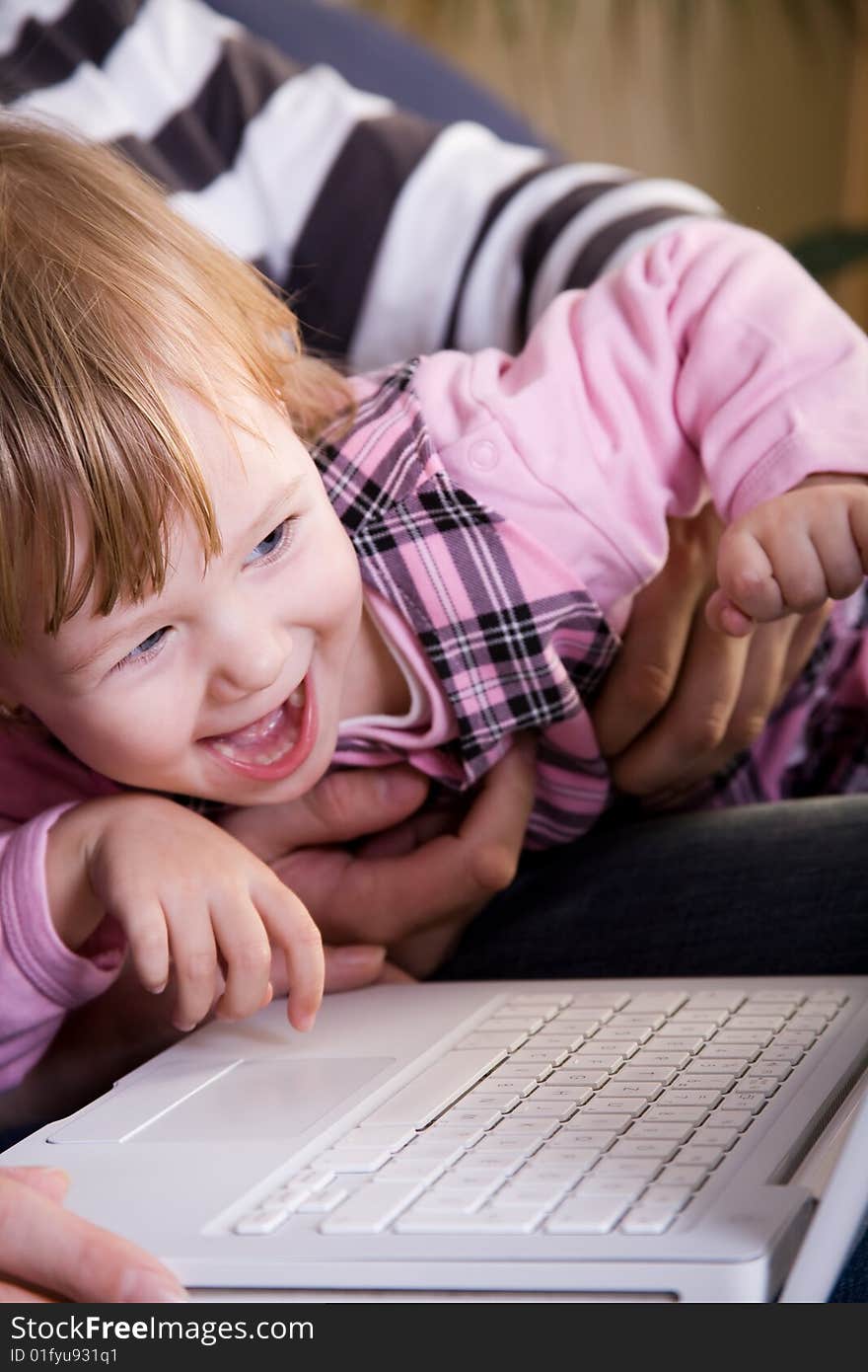 Beutiful little girl play with white laptop computer. Beutiful little girl play with white laptop computer