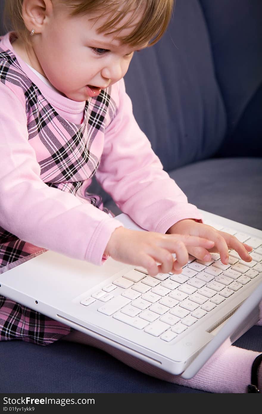 Beutiful little girl play with white laptop computer. Beutiful little girl play with white laptop computer