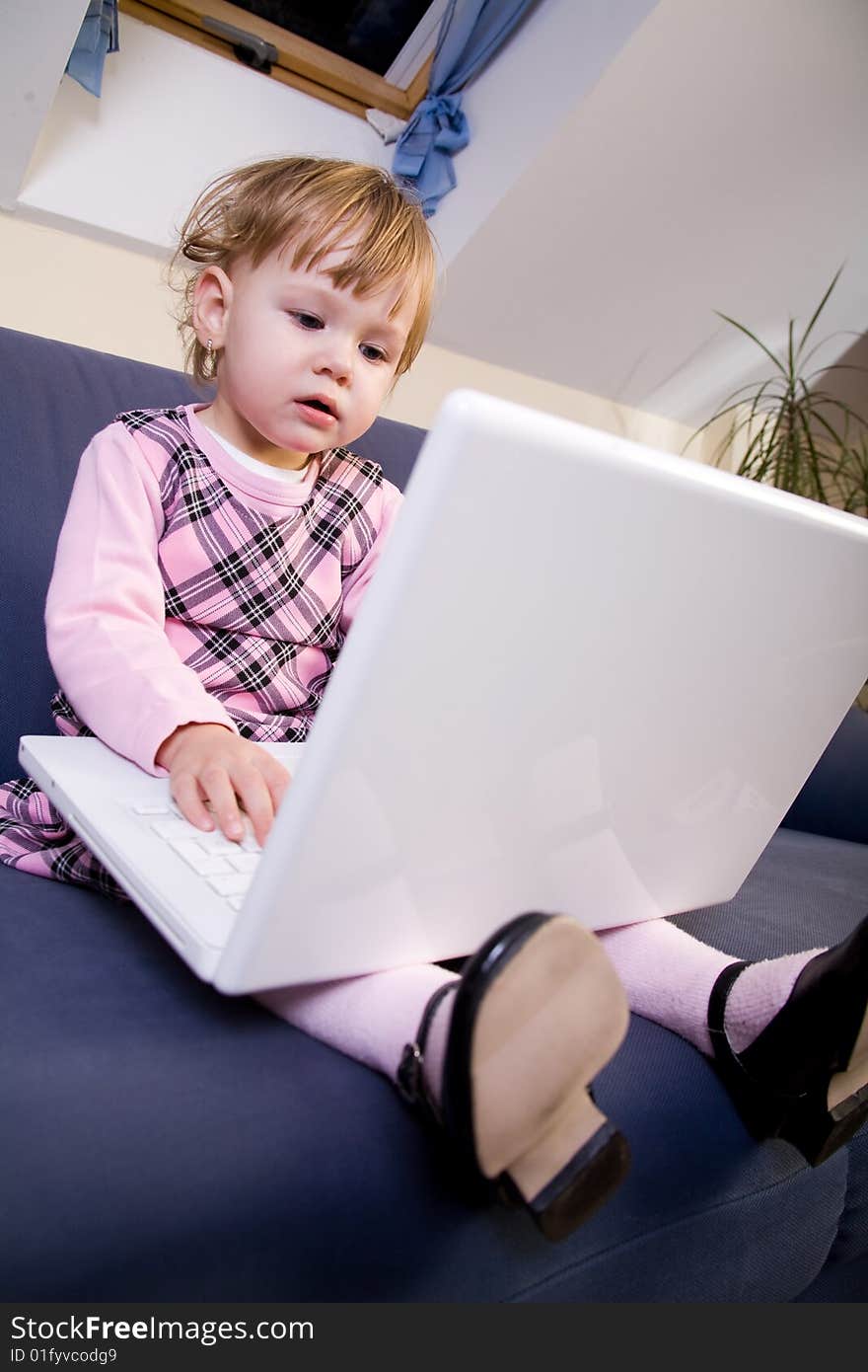 Beutiful little girl play with white laptop computer. Beutiful little girl play with white laptop computer