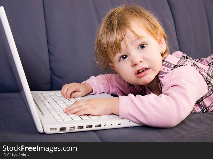 Beutiful little girl play with white laptop computer. Beutiful little girl play with white laptop computer