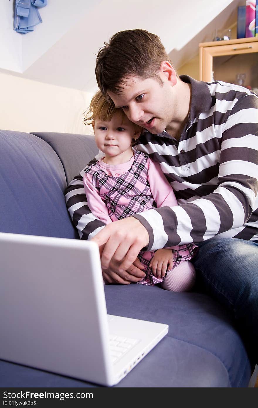 Little girl with father play with a white laptop compute