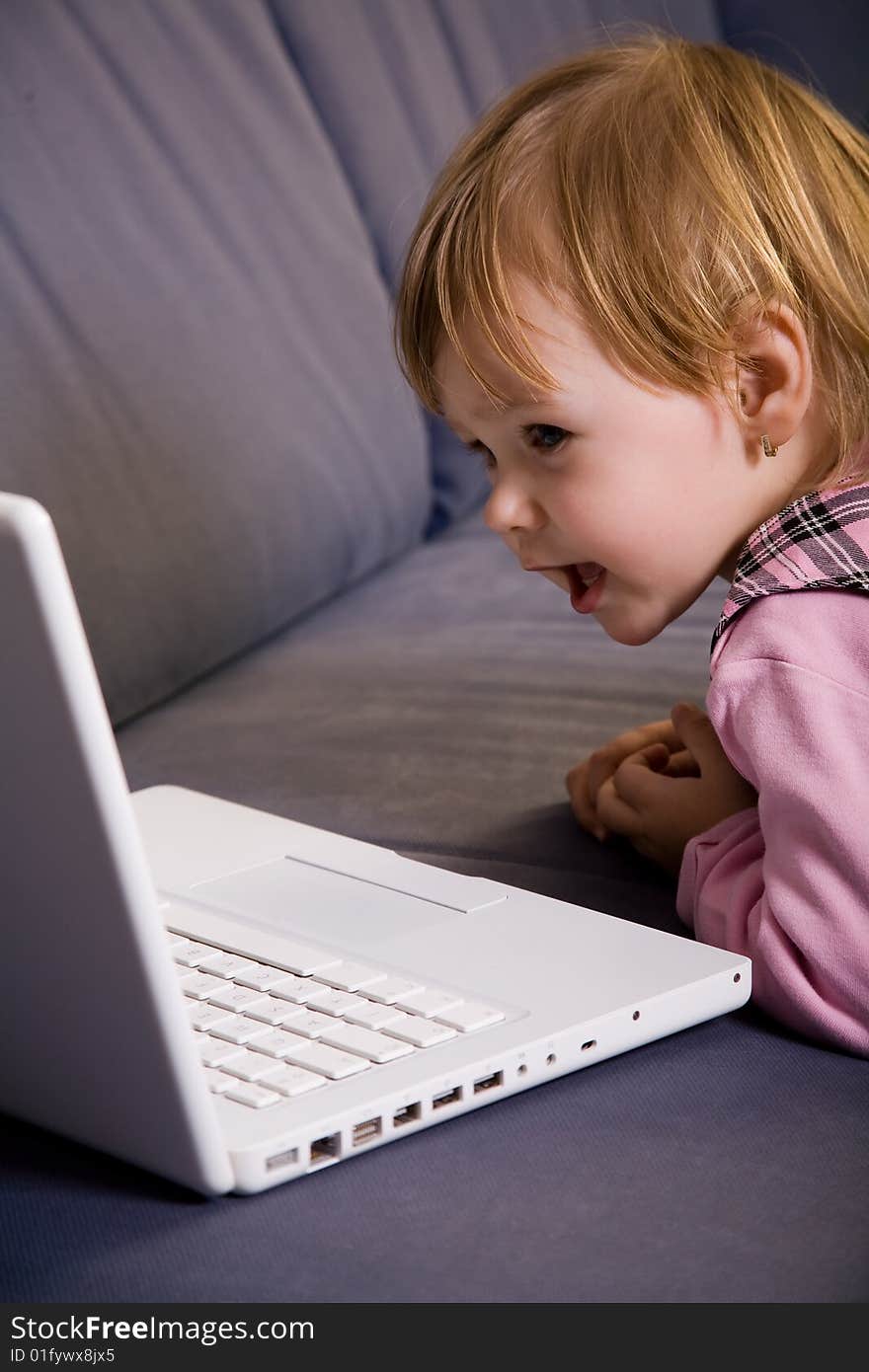 Beutiful little girl play with white laptop computer. Beutiful little girl play with white laptop computer