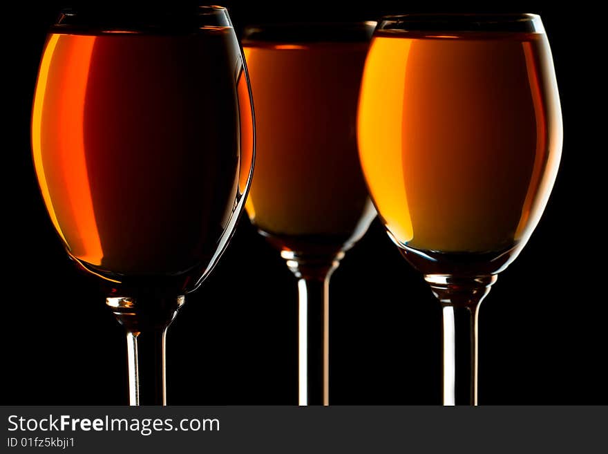 Three small glasses filled with orange liquor on black background. Three small glasses filled with orange liquor on black background