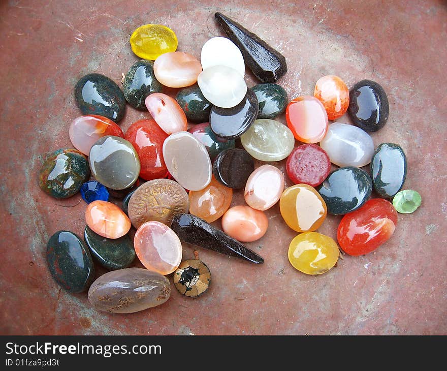 A background of colorful stones of different shape kept in a iron pan. A background of colorful stones of different shape kept in a iron pan