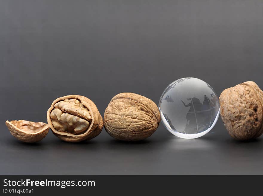 Three walnuts and glassy globe on gray background. Three walnuts and glassy globe on gray background