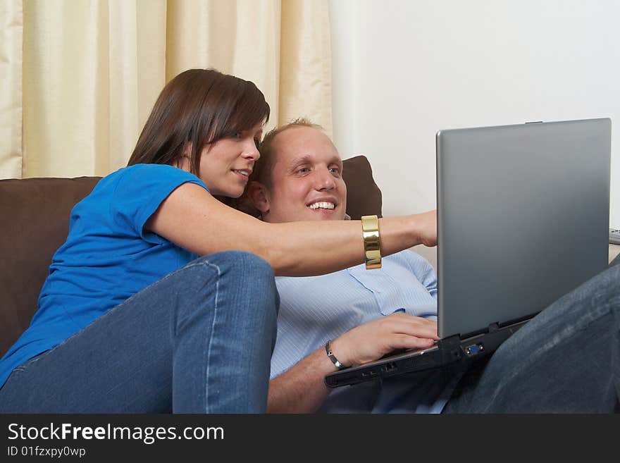 Young couple on the couch at home looking at the laptop!. Young couple on the couch at home looking at the laptop!