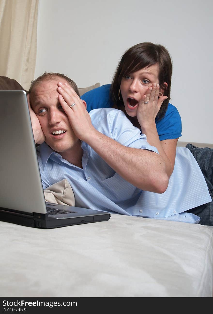 Young couple on the couch at home looking at the laptop!. Young couple on the couch at home looking at the laptop!