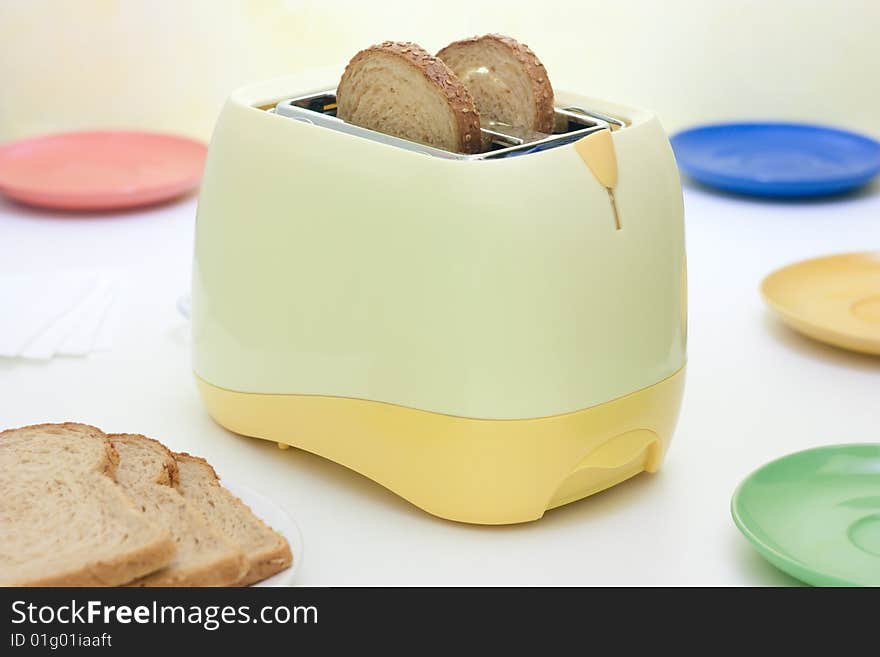 A table setting with breakfast food and toaster. A table setting with breakfast food and toaster