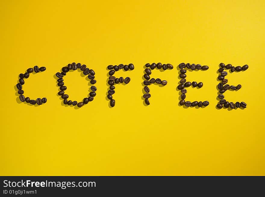 Coffee written with beans on yellow background.