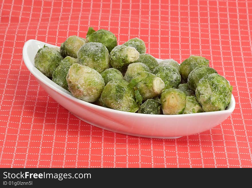 Frozen Brussels sprouts in a bowl on red background