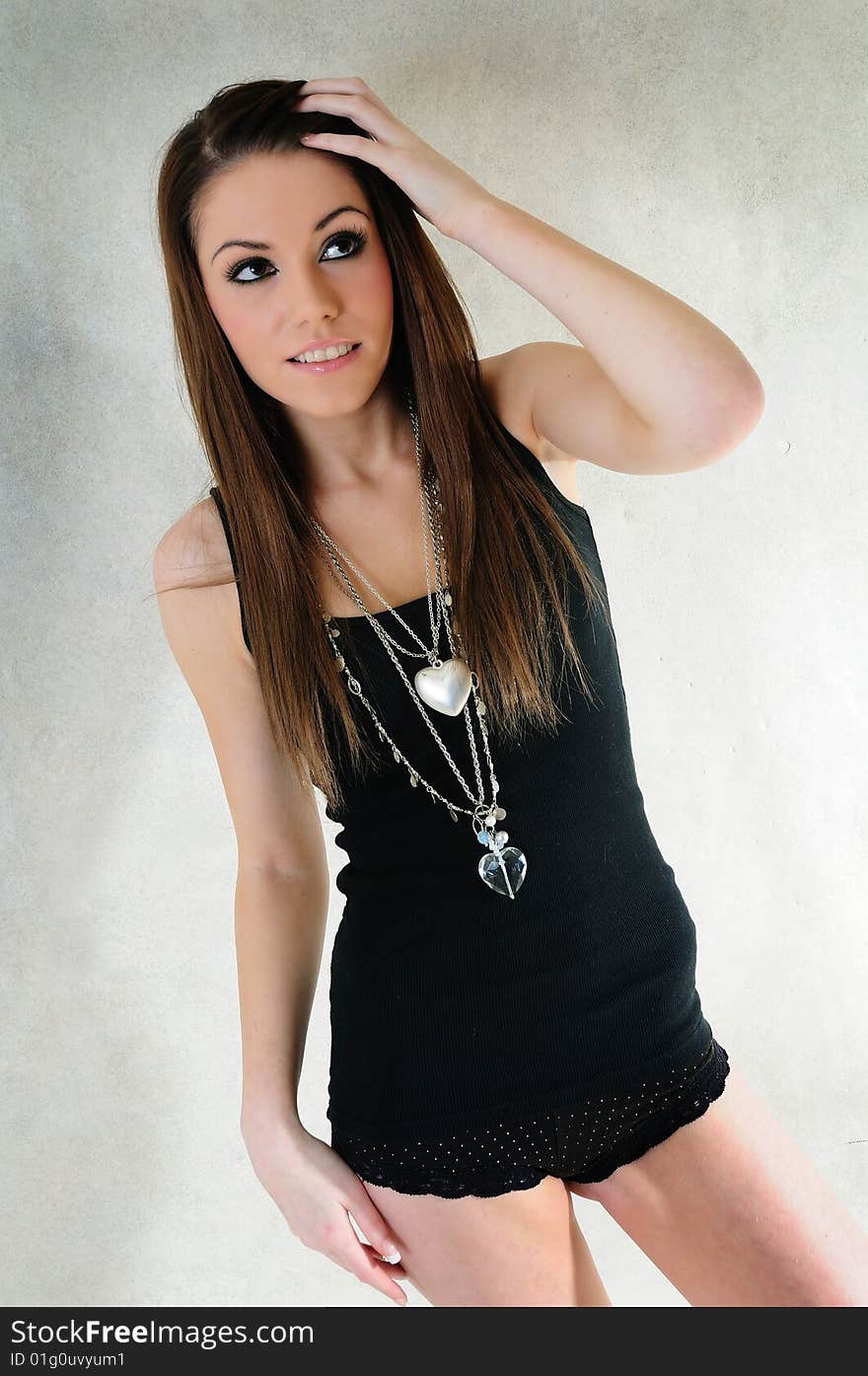 Female model standing in a studio grinning and looking away from the camera