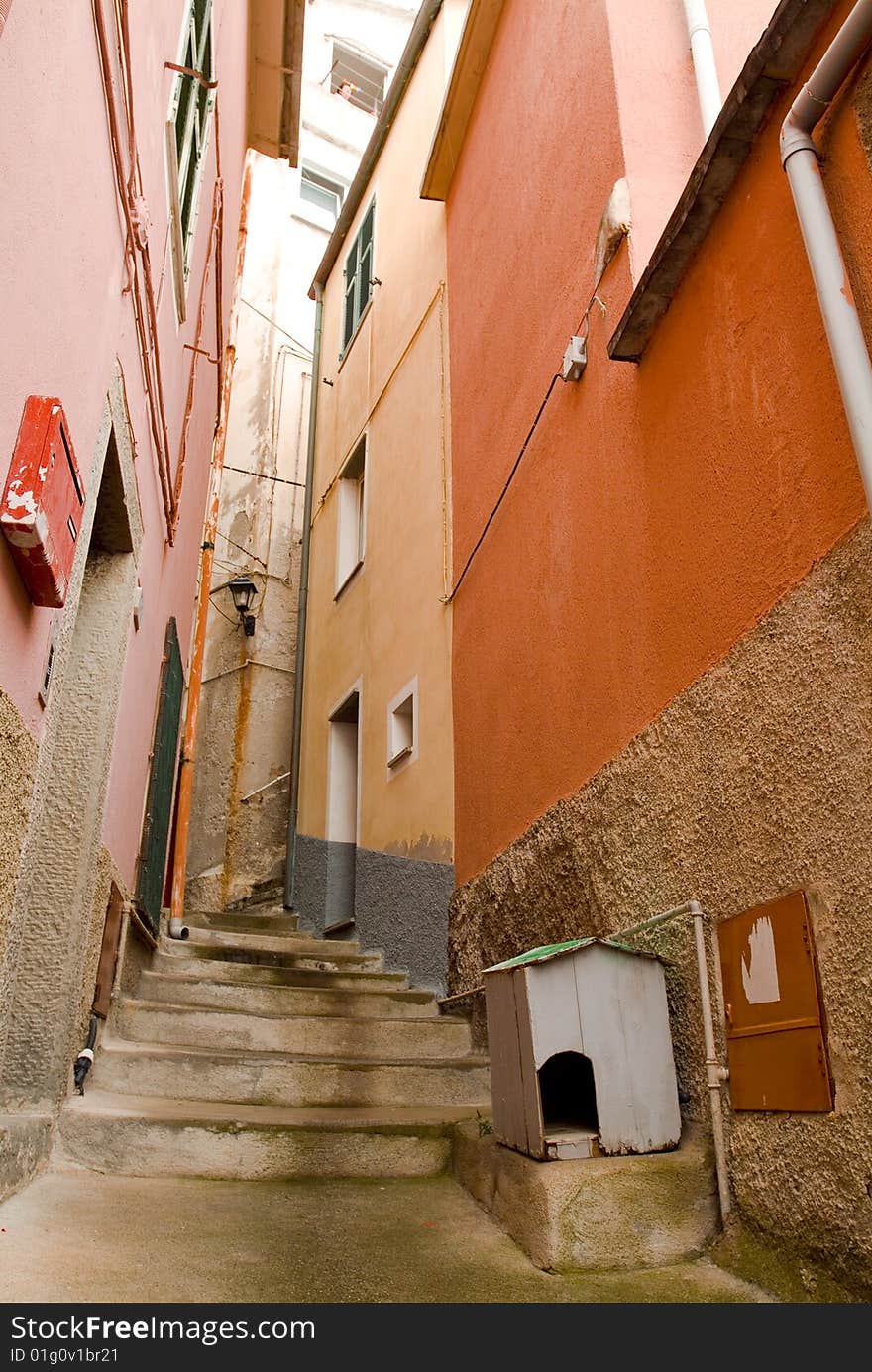 Dog house on in a narrow alley with stairs, Manarola, Italy. Lady in window many stories above, postbox across. Dog house on in a narrow alley with stairs, Manarola, Italy. Lady in window many stories above, postbox across.