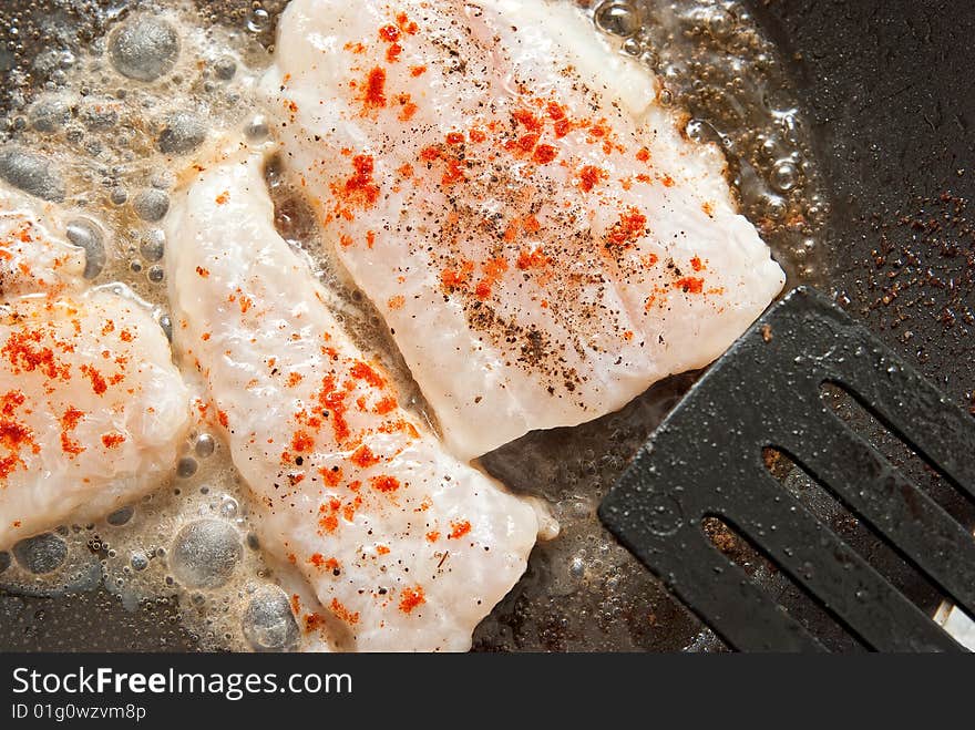 Fried fish with spices in the cooking pan