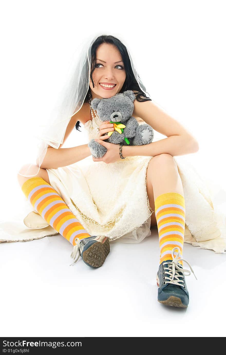 Funny dreamy beautiful bride wearing old running shoes and holding a toy in her hands. Funny dreamy beautiful bride wearing old running shoes and holding a toy in her hands