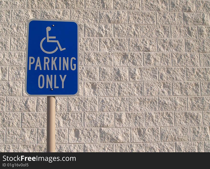 Blue handicap parking sign with a white textured concrete block background that can be used for copy space. Blue handicap parking sign with a white textured concrete block background that can be used for copy space.