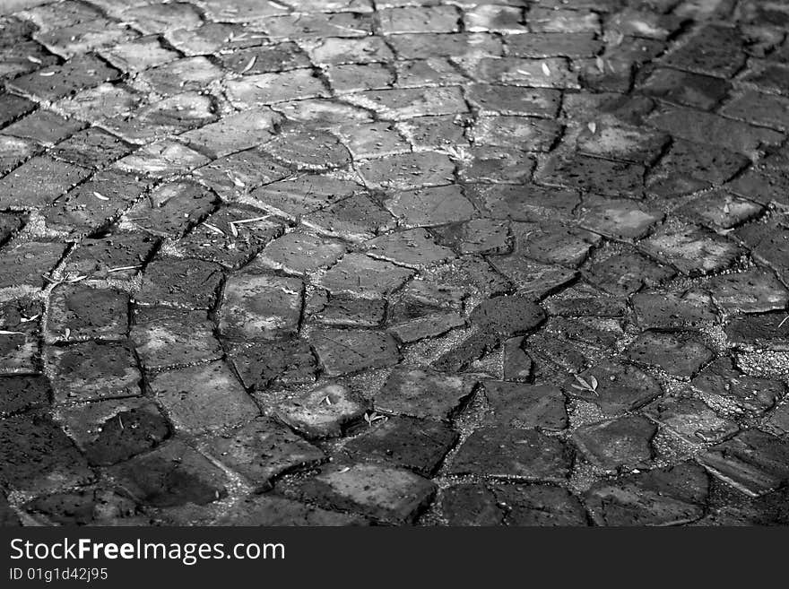 Black and white image of paving laid with broken bricks. There is a circular pattern visible. Black and white image of paving laid with broken bricks. There is a circular pattern visible