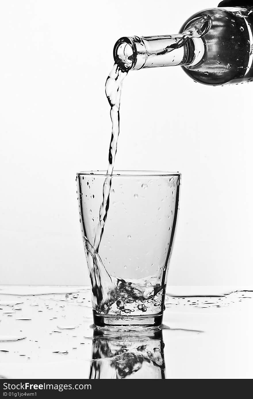 Glass of pouring water with reflection (white background)