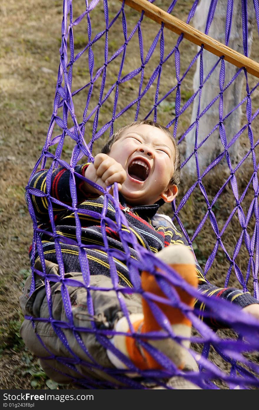 A picture of a little chinese boy laughing and having great fun in hammock. A picture of a little chinese boy laughing and having great fun in hammock