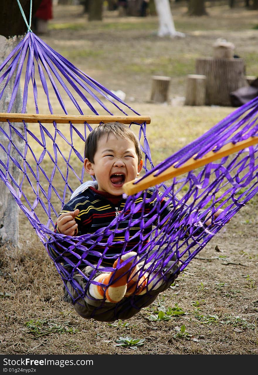 A picture of a little chinese boy laughing and having great fun in hammock. A picture of a little chinese boy laughing and having great fun in hammock