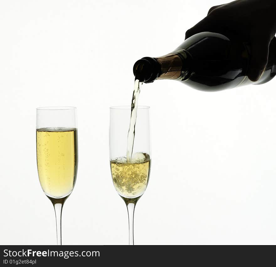 Champagne being poured into a flute, isolated on a white background.