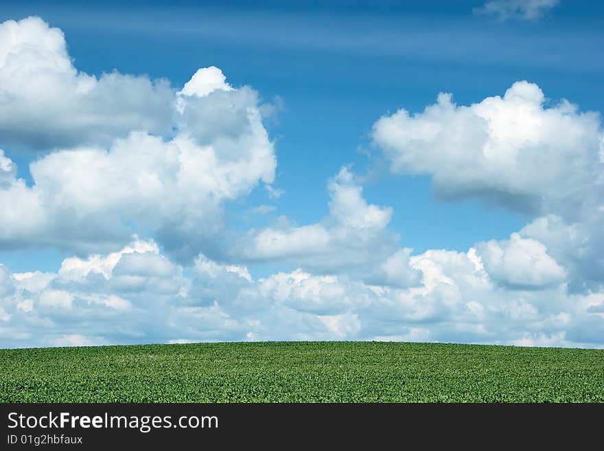 Green hill under blue cloudy sky