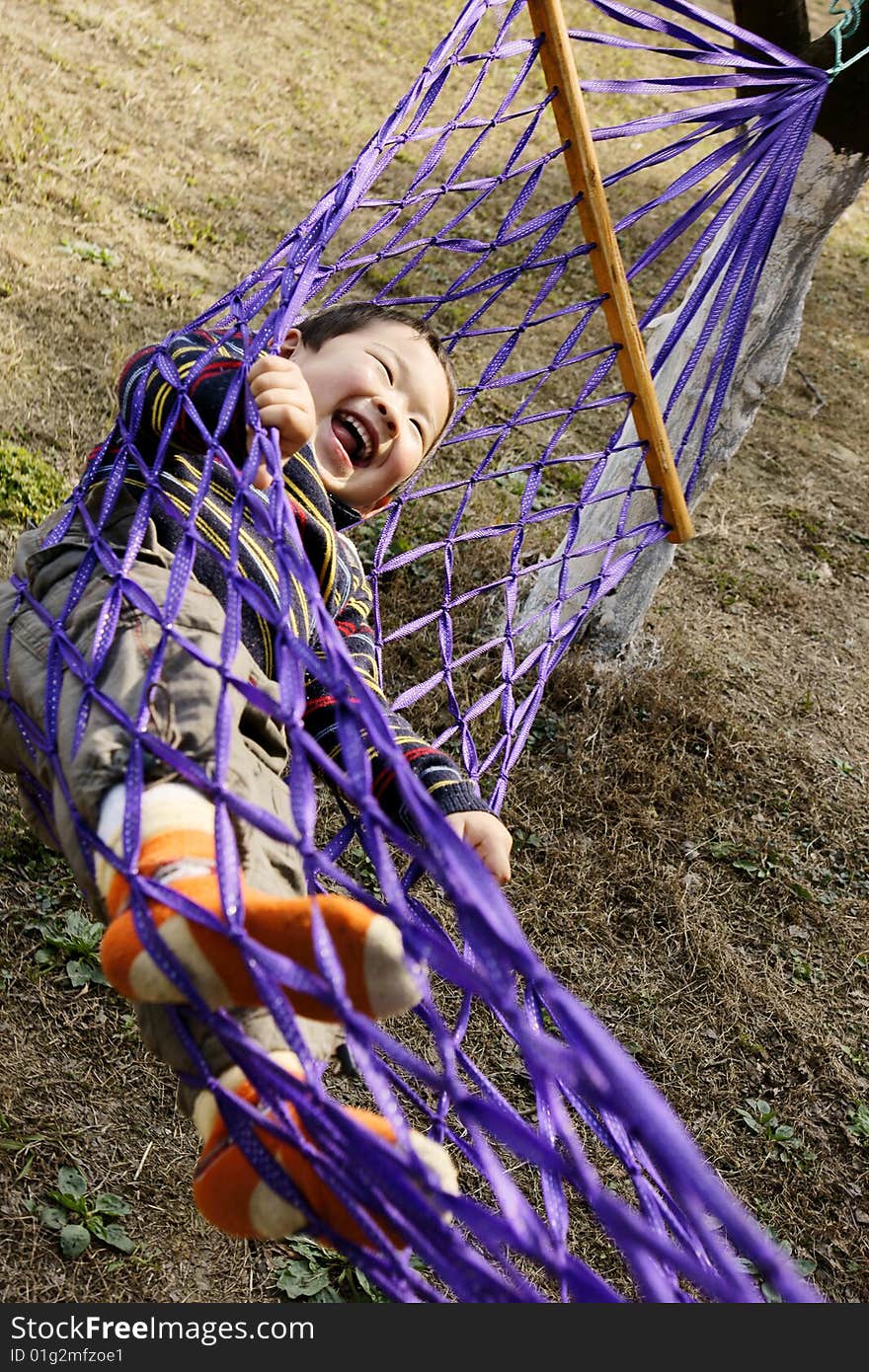 A picture of a little chinese boy laughing and having great fun in hammock. A picture of a little chinese boy laughing and having great fun in hammock