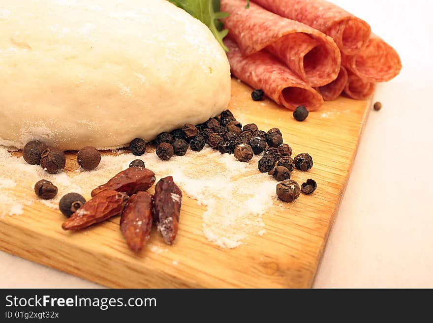 Pizza dough, pepper, salami and rukola on the board. Pizza dough, pepper, salami and rukola on the board.