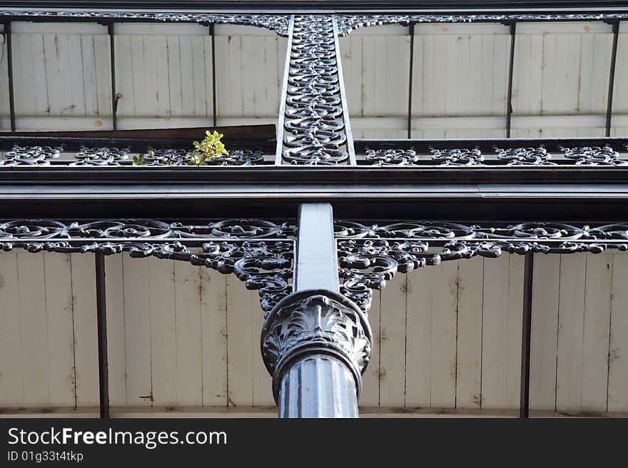 Black, wrought iron post supporting a ceiling, with intricate scrollwork. Black, wrought iron post supporting a ceiling, with intricate scrollwork