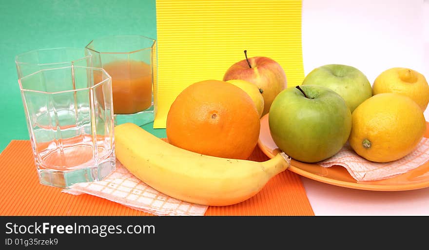 Fresh seasonal fruit, apples, bananas, orange and glass fruit juice on reflective underground