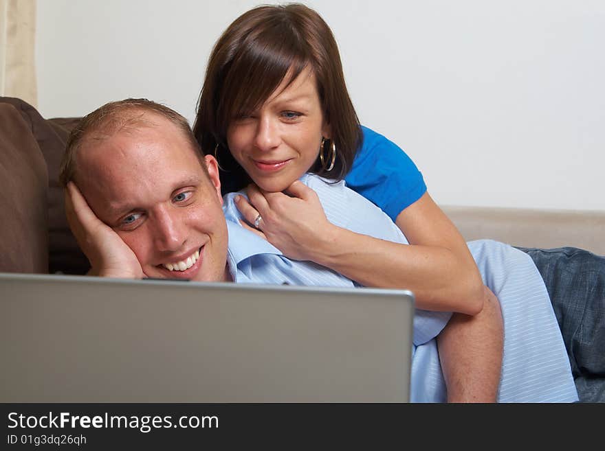 Young couple on the couch at home looking at the laptop!. Young couple on the couch at home looking at the laptop!