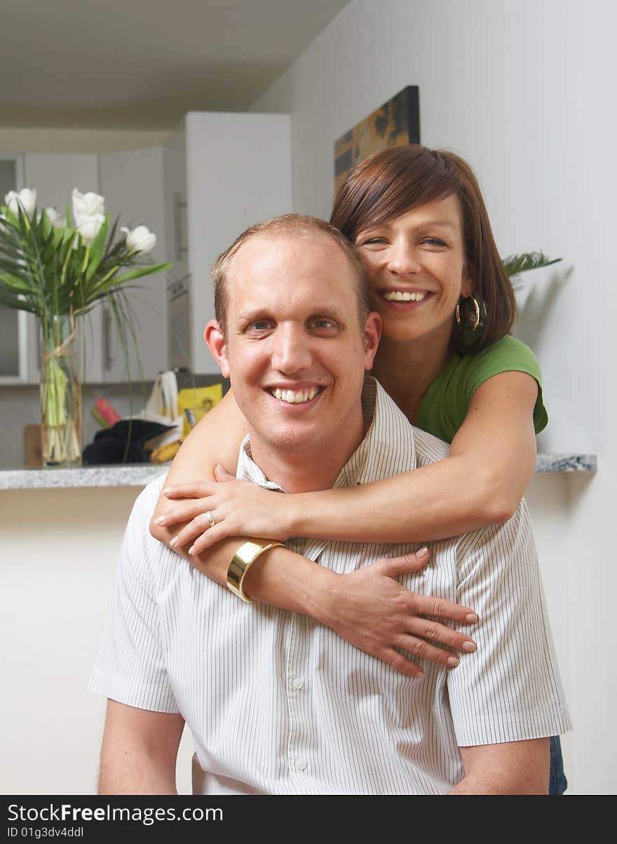 A young couple in love in their new appartment. The woman hugs the man from behind. A young couple in love in their new appartment. The woman hugs the man from behind.