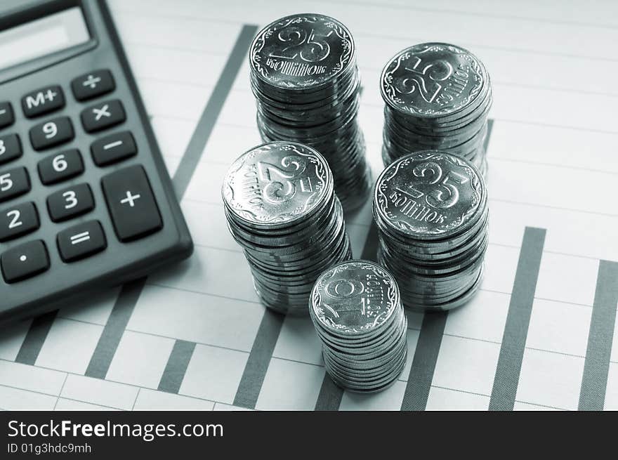 Brilliant coins of yellow colour on a sheet of paper with the diagramme and the calculator. Brilliant coins of yellow colour on a sheet of paper with the diagramme and the calculator.