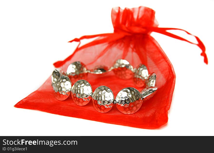 An image of a metal bracelet  with a red bag over white background