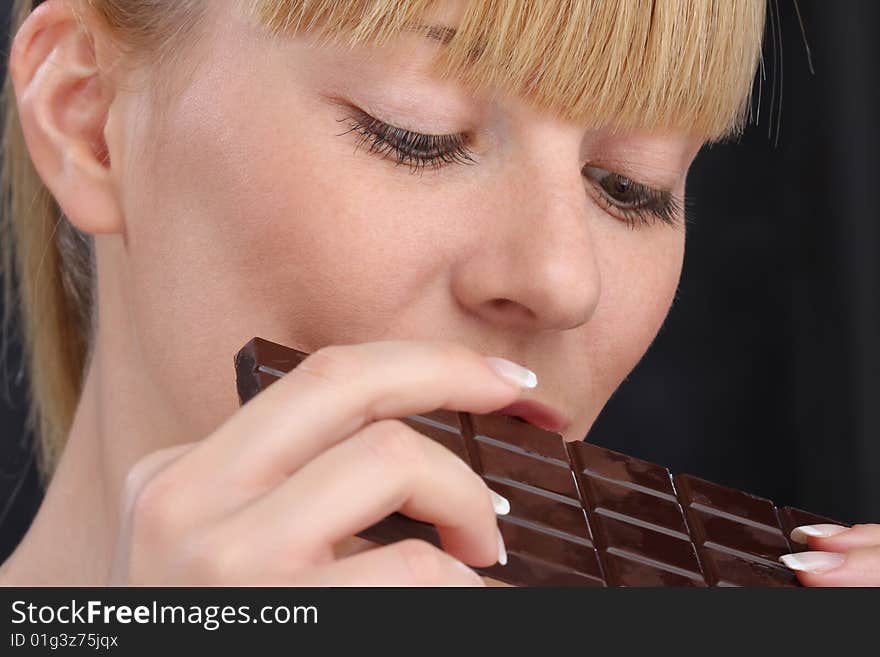 Beautiful blond girl eating chocolate close up