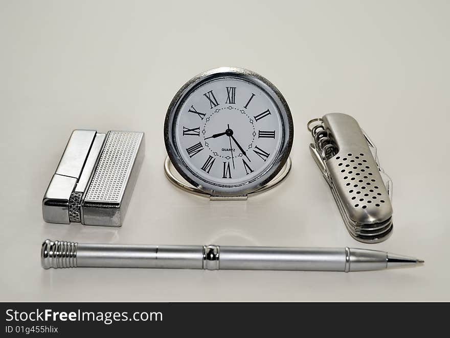 A close-up of the men's silvery accessories: watch, knife, lighter, pen. A close-up of the men's silvery accessories: watch, knife, lighter, pen.