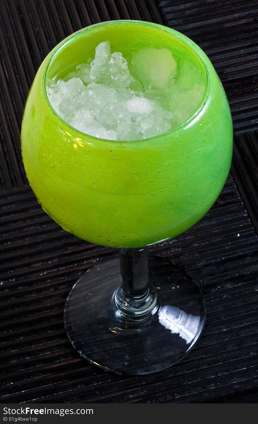 A frozen margarita in a decorative glass on a hardwood surface.