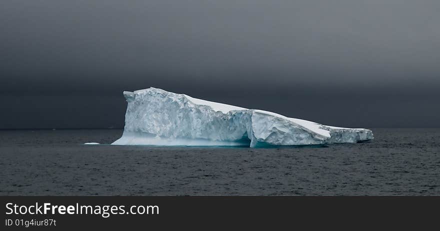 A tabular iceberg slanting into the sea in Antarctica. A tabular iceberg slanting into the sea in Antarctica.