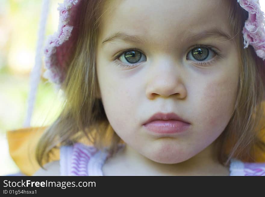 Portrait of a beautiful baby girl having fun on very colourful swing and wearing a pink hat. Portrait of a beautiful baby girl having fun on very colourful swing and wearing a pink hat