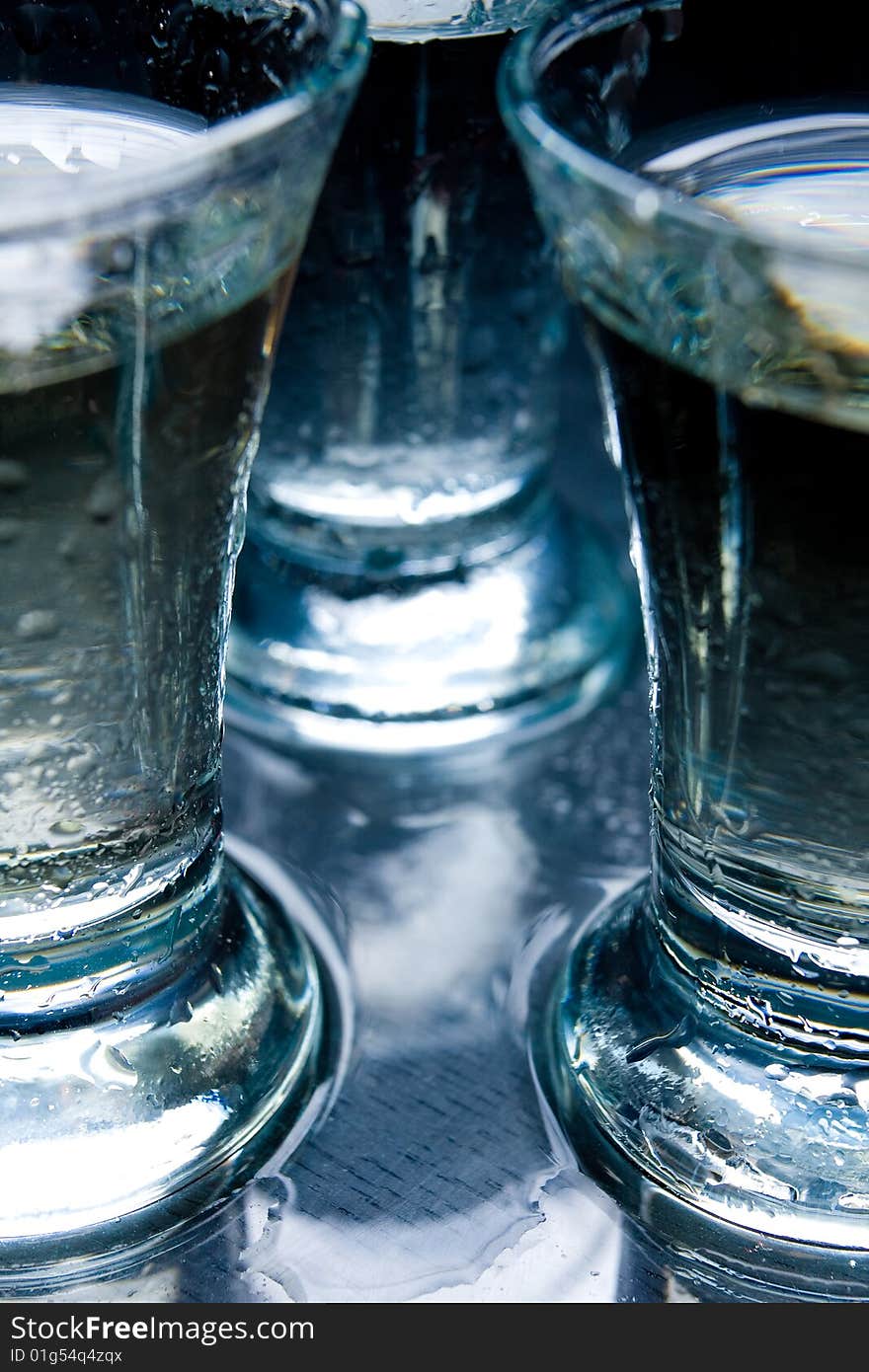 Several short glasses on the wet glass table. Several short glasses on the wet glass table