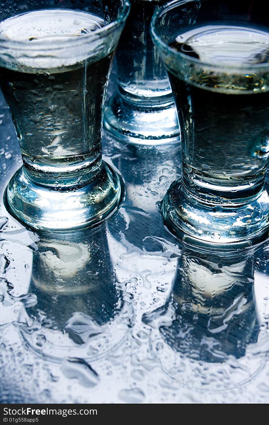 Several short glasses on the wet glass table. Several short glasses on the wet glass table