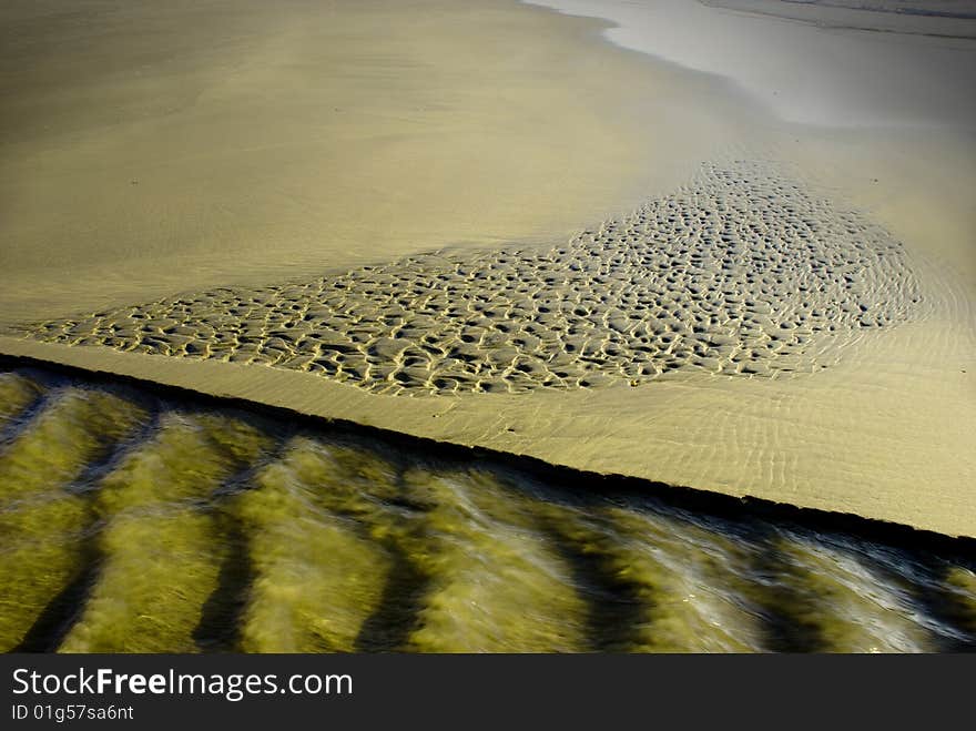 Shallow spring water flowing over sand on a beach. Shallow spring water flowing over sand on a beach