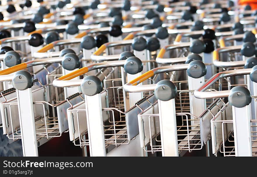 A closeup view of the handles of several rows of supermarket shopping carts. A closeup view of the handles of several rows of supermarket shopping carts