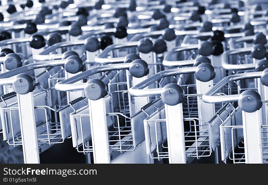 A closeup view of the handles of several rows of supermarket shopping carts. A closeup view of the handles of several rows of supermarket shopping carts