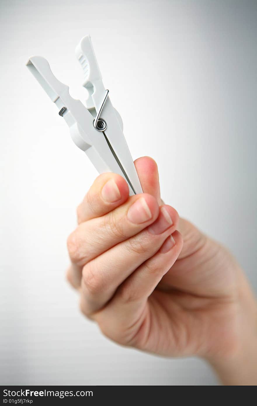 White clothespin in hand on grey background