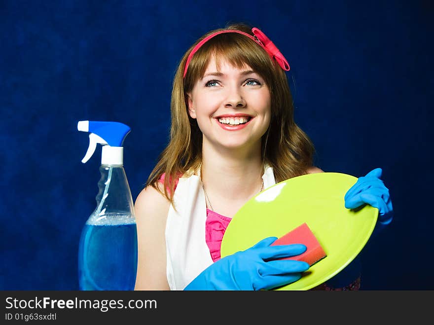 Beautiful young housewife washing the dishes against blue background