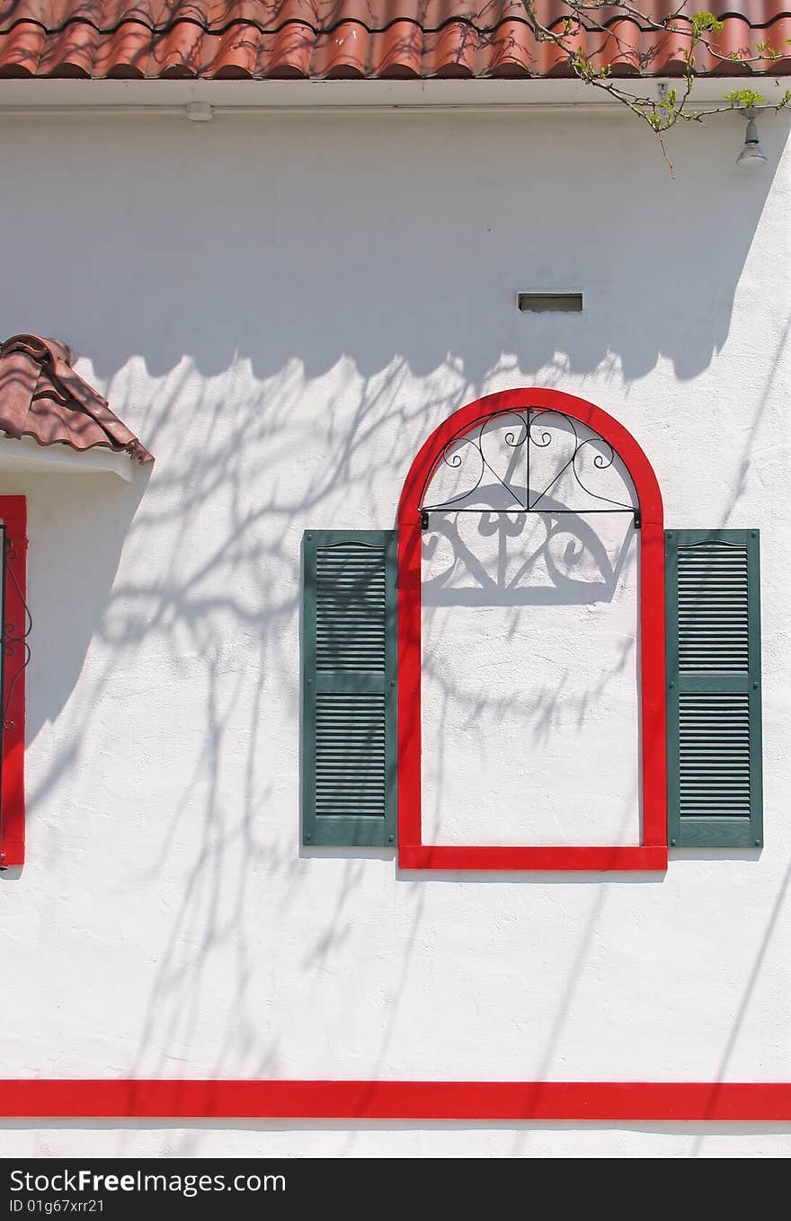 A false window in red with green shutters on stucco. A false window in red with green shutters on stucco