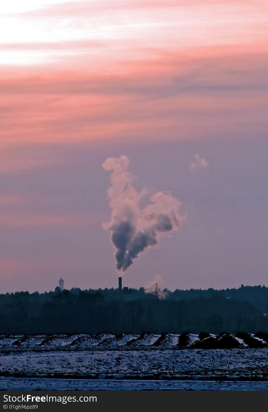 A smoking chimney in the light of a sunset. A smoking chimney in the light of a sunset